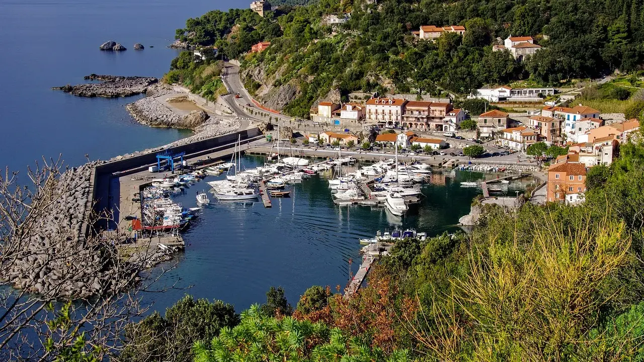 Maratea: un incantevole porto con barche ormeggiate, case colorate e vegetazione lussureggiante. Scopri cosa vedere nel suo centro storico.