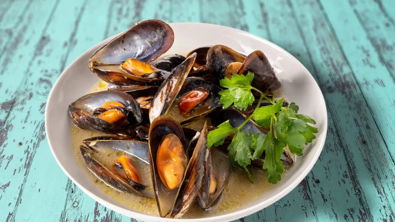 Un plat de moules au roquefort, garni de persil frais, baignant dans une sauce crémeuse.