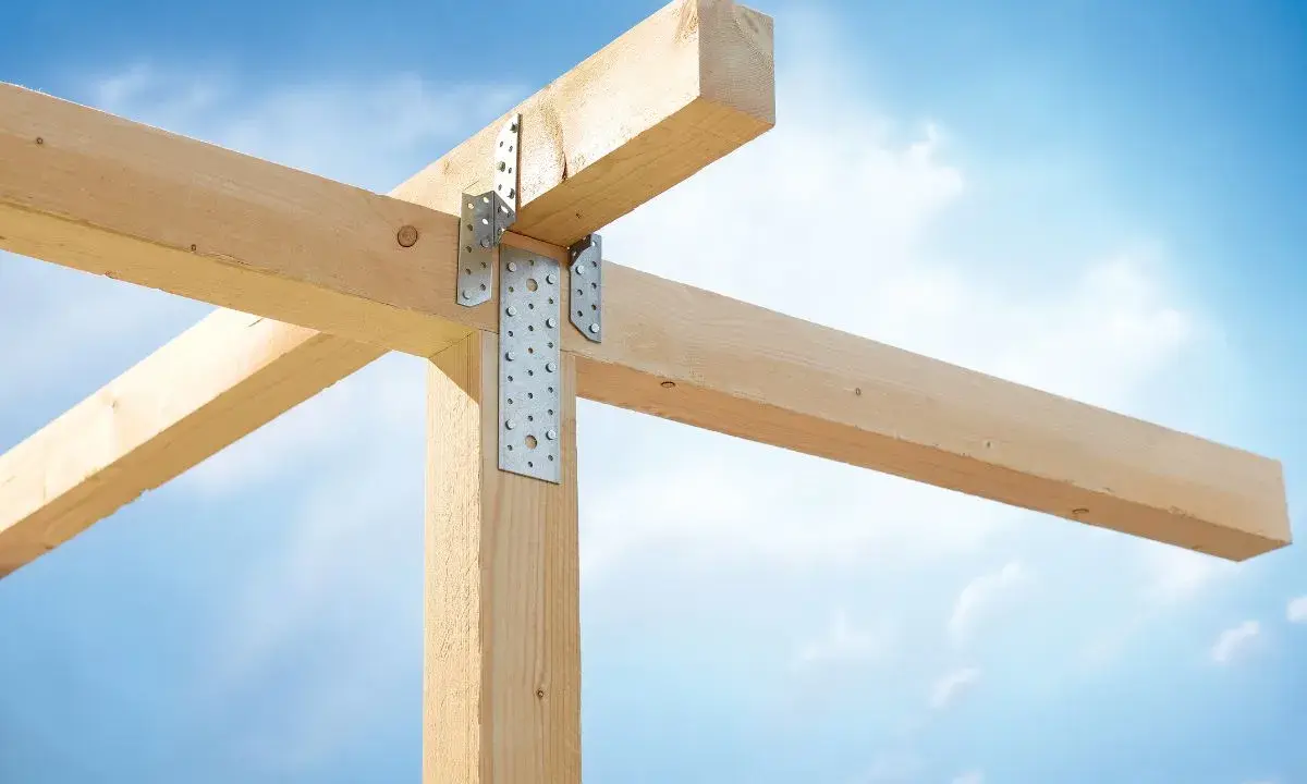 Stabile Holzverbindungen mit Metallwinkeln sichern die Balkenkonstruktion gegen den blauen Himmel.