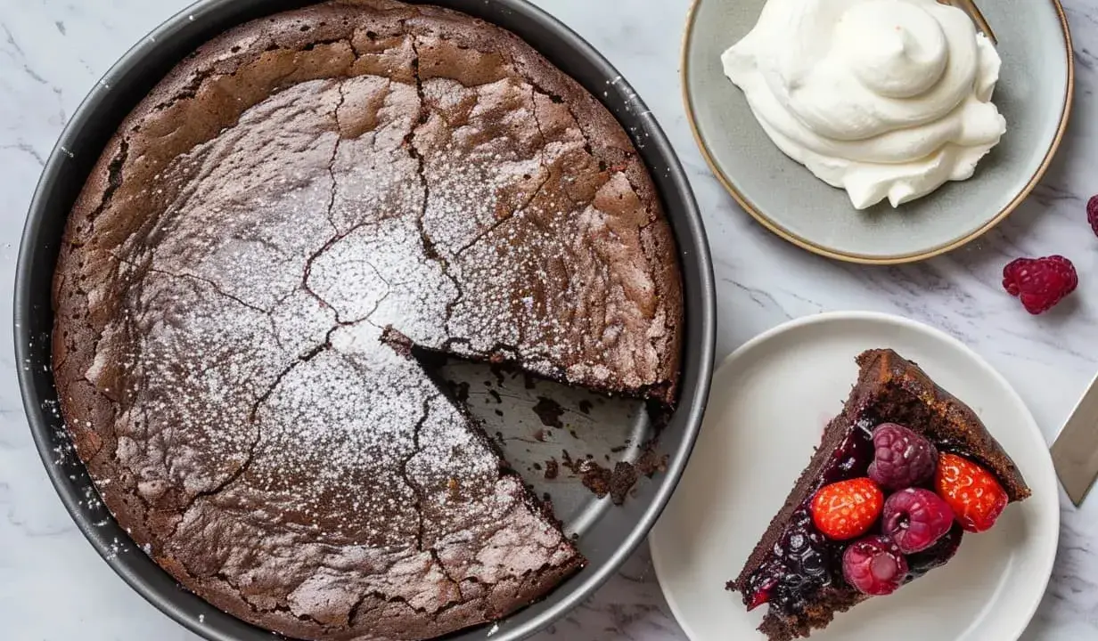 En saftig kladdkaka med pudersocker, serverad med vispad grädde och färska bär. Ett perfekt kladdkaka recept för alla chokladälskare.