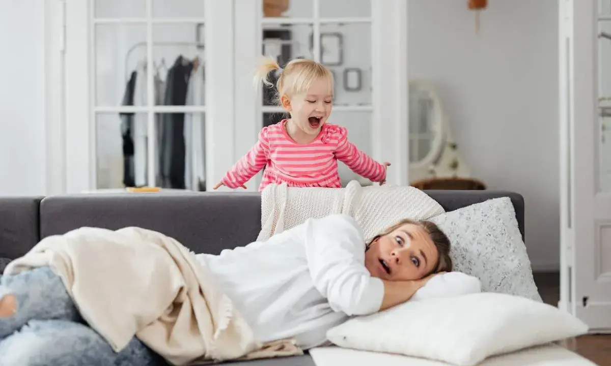 Niña emocionada sobre el sofá, mientras su madre se asusta. ¡Un día típico con el horario para niños en casa!