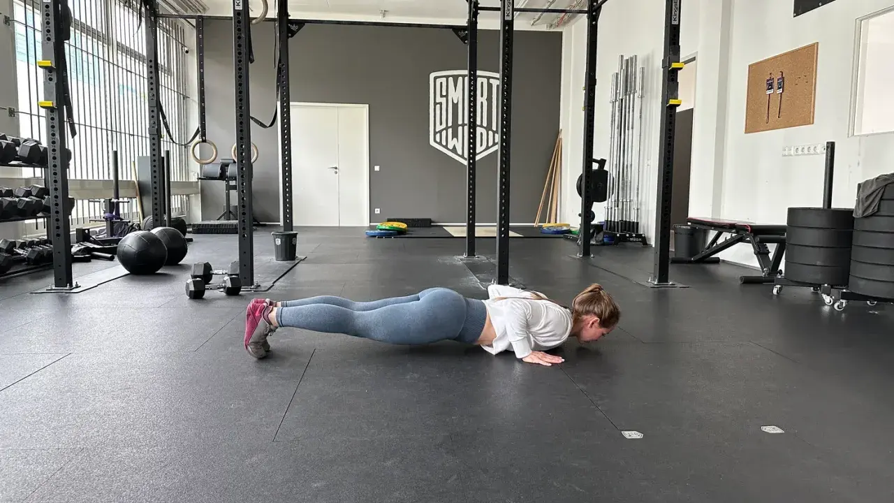 Frau macht Liegestütze im Fitnessstudio, ein Teil ihres plyometrischen Trainings.