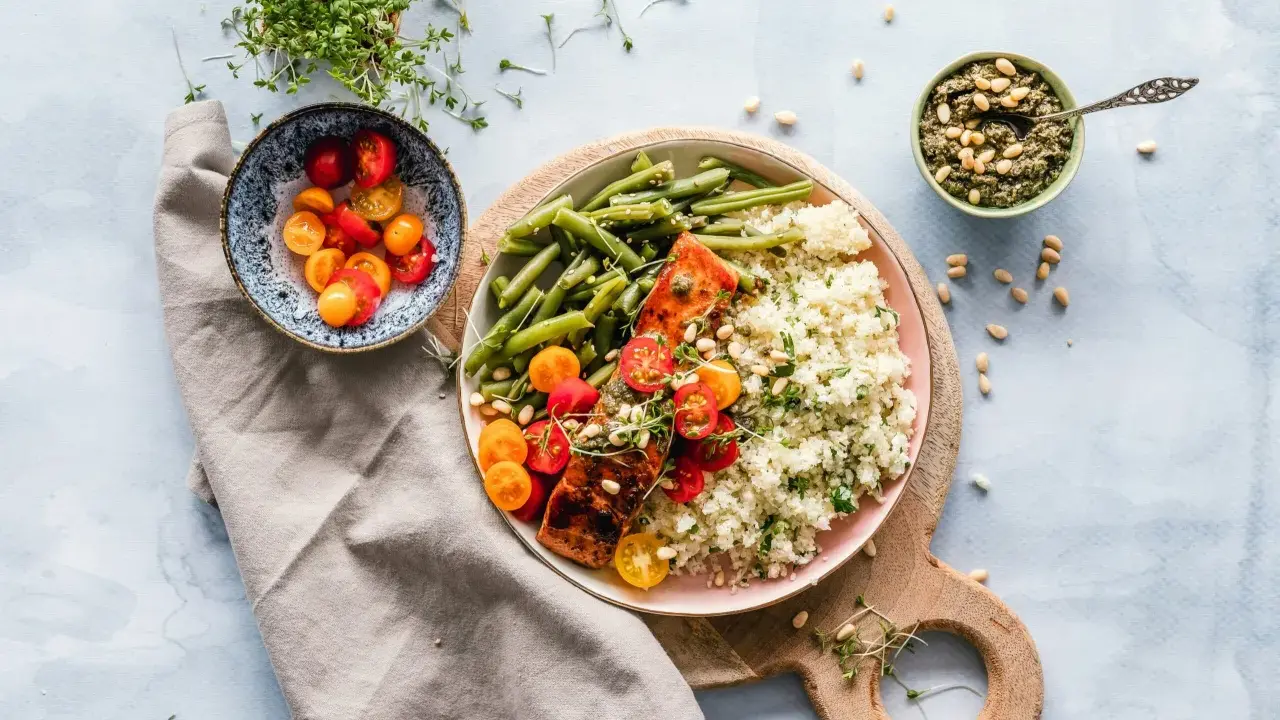 Un délicieux repas parisien : saumon grillé, haricots verts, riz et tomates cerises, accompagné de pesto et de pousses fraîches.