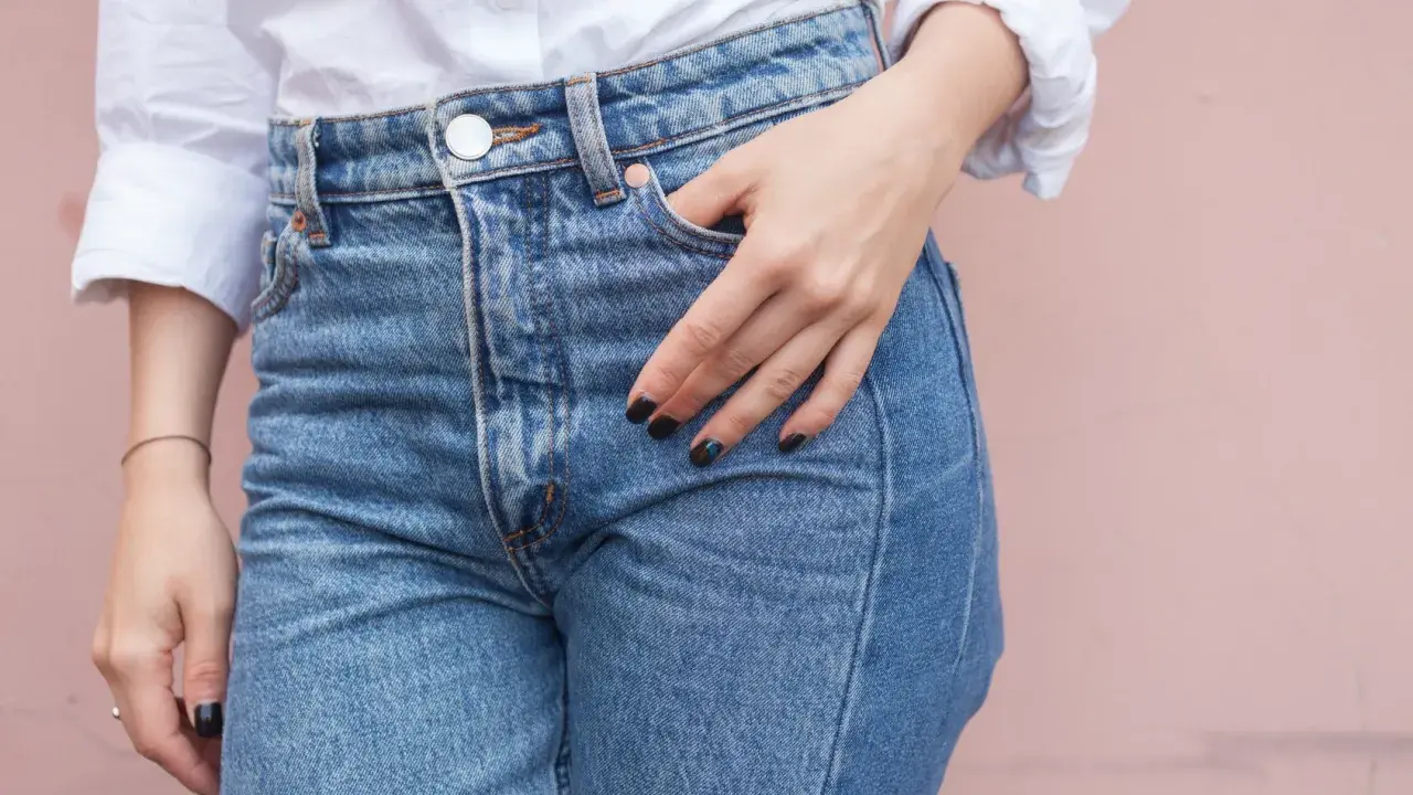 En hand vilar i fickan på ett par ljusblå jeans. Kanske är det en ny trend, jeans i frysen, för att få dem extra krispiga?