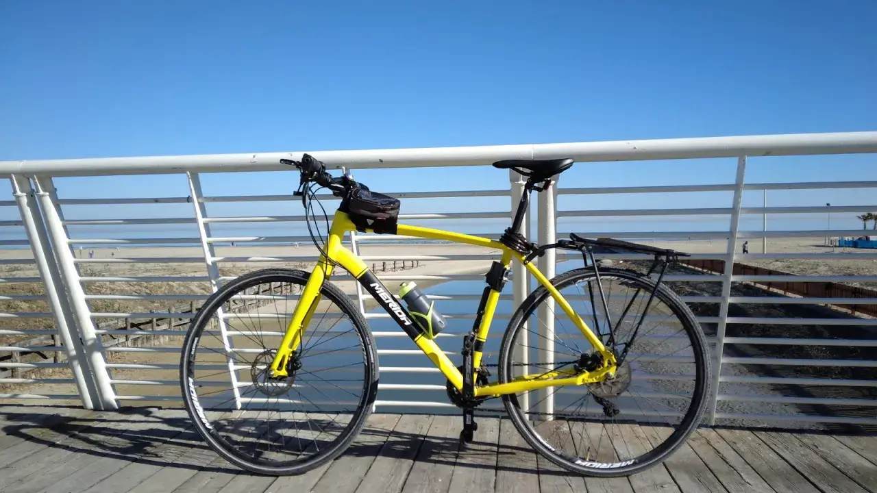 Bicicletta gialla pronta per un giro a Rimini Cattolica, con il mare e la spiaggia sullo sfondo.