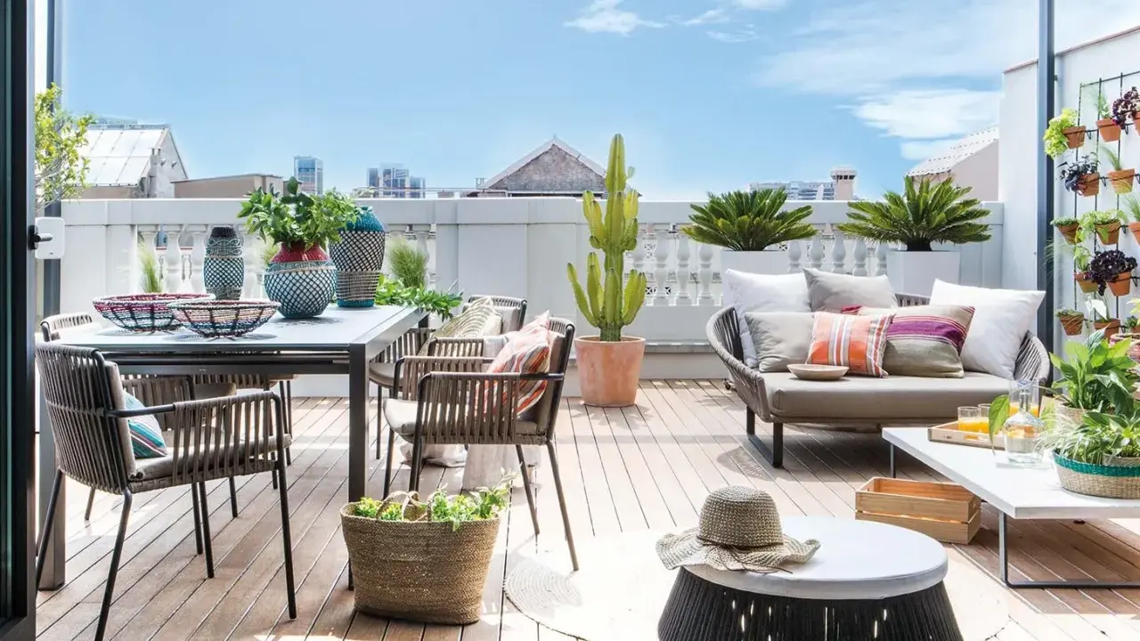 Ideas para decorar una terraza: mesa, sillas, sofá, plantas y cestas crean un espacio acogedor y moderno.