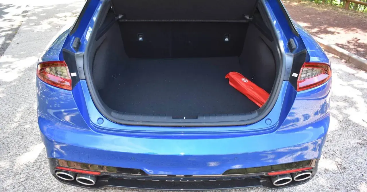 Maletero abierto de un Kia Stinger azul, con un botiquín rojo en el interior.