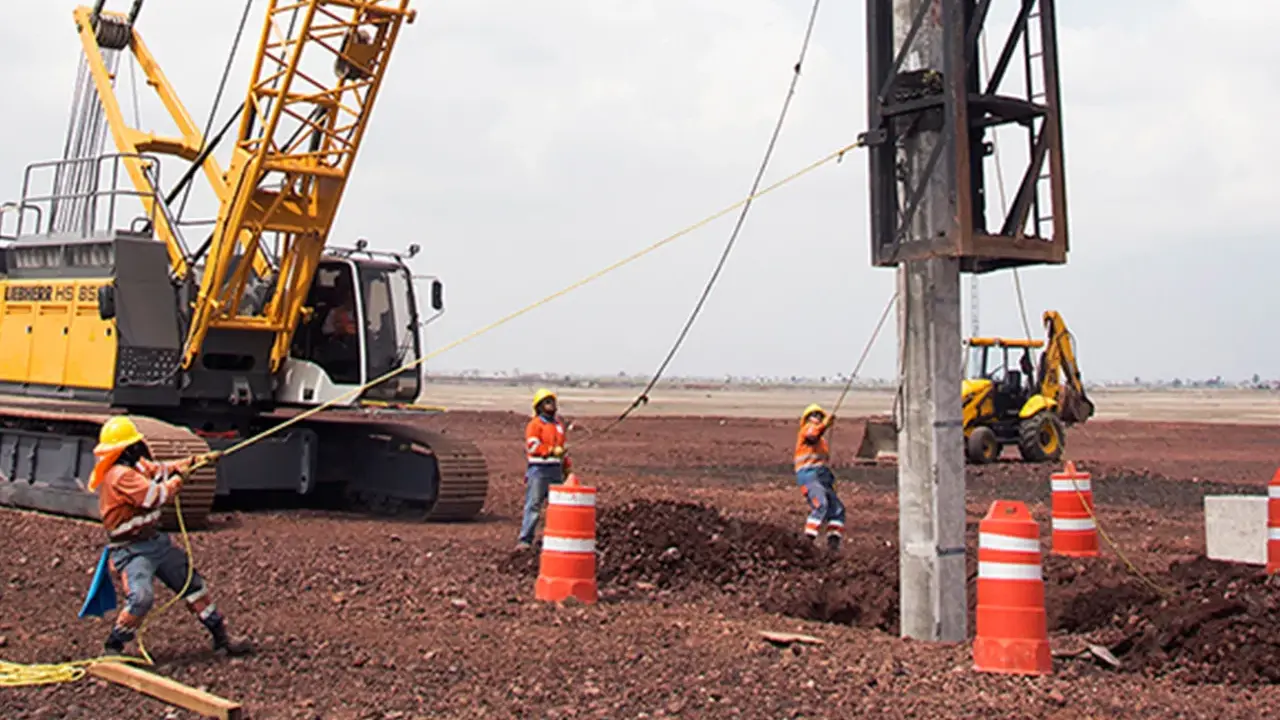 Trabajadores y maquinaria pesada instalan pilotes para cimentaciones profundas en un sitio de construcción.