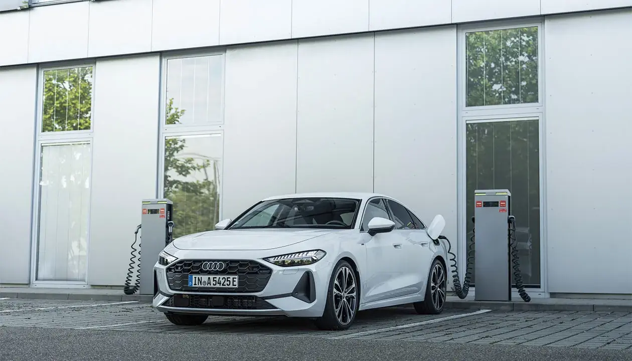 Ein weißer Audi lädt an einer Ladestation. Das zeigt, was ist ein Hybridauto: flexibel und umweltfreundlich unterwegs.