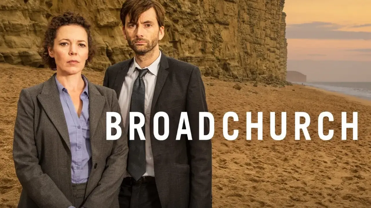 Två poliser står på en strand framför en klippa. Serien Broadchurch är en av de bästa kriminalserier topplista.