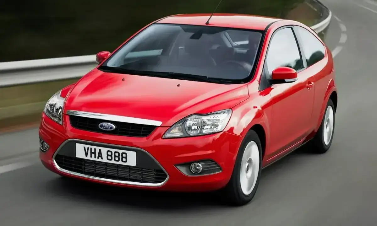 Czerwony Ford Focus MK2 1.6 benzyna w wersji 3-drzwiowej, jadący po zakręcie drogi.