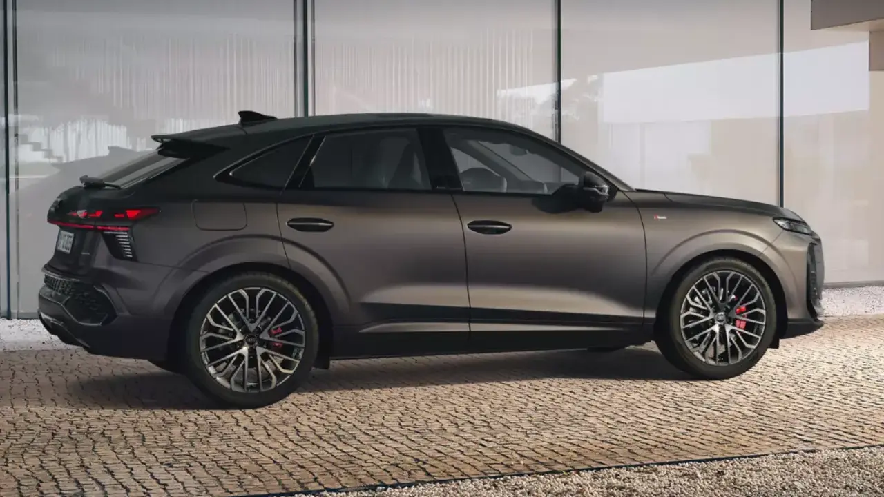 Elegancki Audi Q3 2025 w ciemnym kolorze, z dynamiczną linią nadwozia, prezentuje się na tle nowoczesnej architektury.