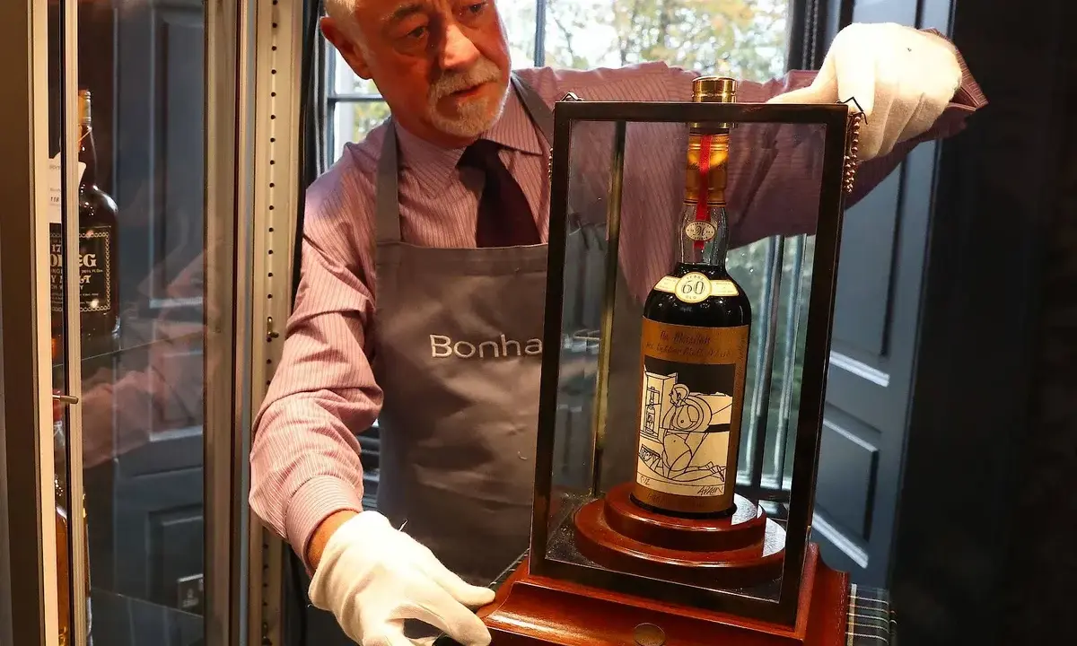 Mann mit weißen Handschuhen präsentiert eine Flasche des teuersten Weins der Welt, eine seltene Macallan 60 Year Old.