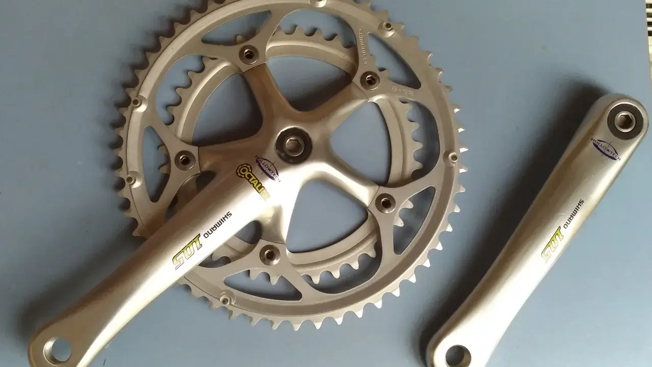Srebrna korba rowerowa Shimano 105 z technologią Hollowtech 1 i zębatkami.