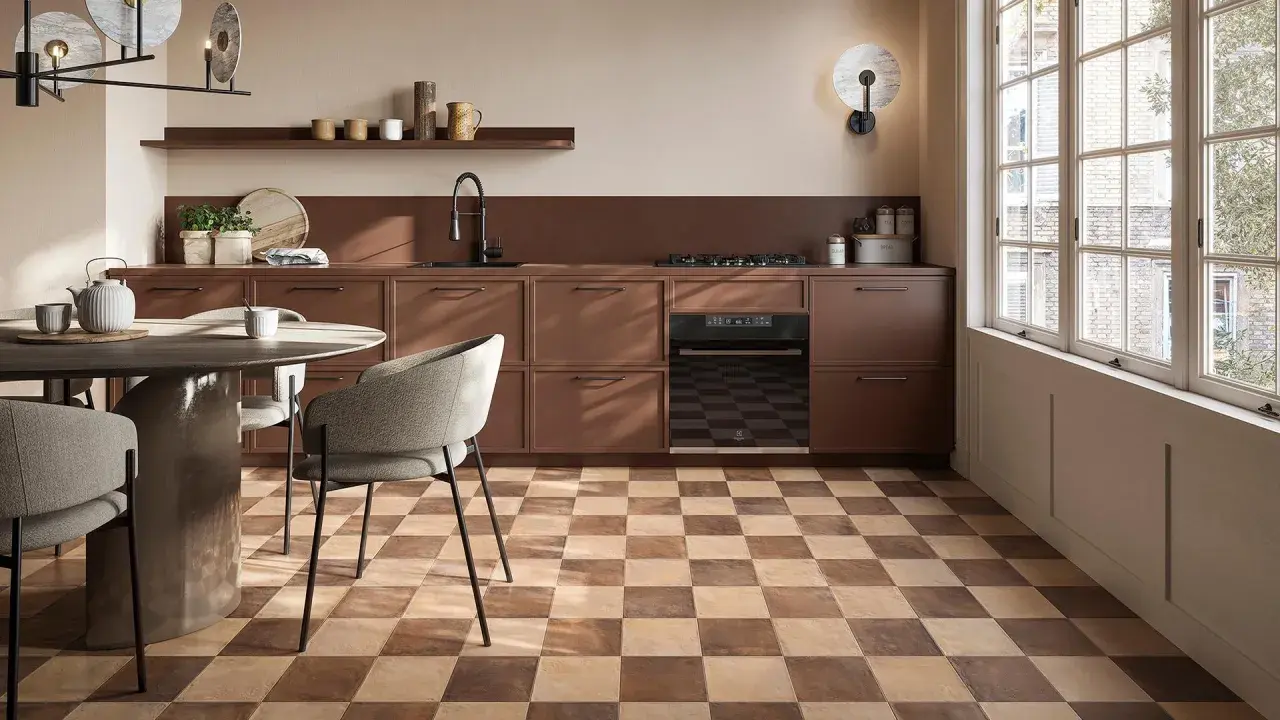 Cucina moderna con pavimento a scacchiera che crea una **tabella colori caldi**. Mobili marroni, tavolo rotondo e sedie grigie.