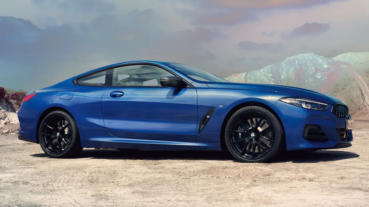 Błękitne BMW 840i z czarnymi felgami na tle pustynnego krajobrazu i gór.