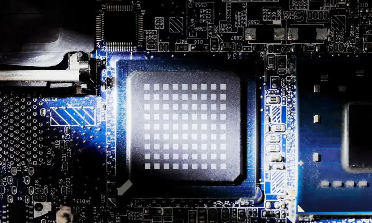 Gros plan sur un processeur d'ordinateur, montrant sa grille de contacts et les circuits imprimés environnants. Le nombre de cœurs du processeur est caché sous cette surface complexe.