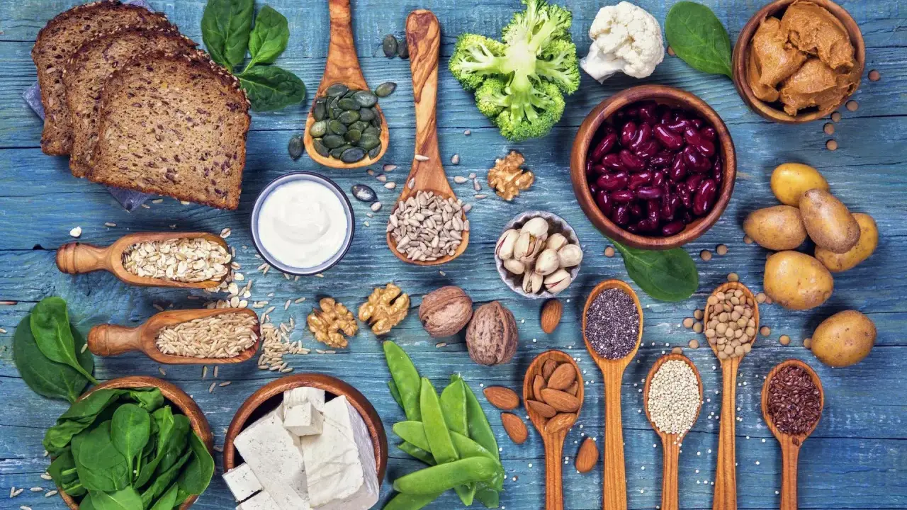Różnorodne produkty bogate w białko dla wegetarian: tofu, soczewica, fasola, orzechy, nasiona, płatki owsiane, ryż, chleb pełnoziarnisty, jogurt, szpinak, brokuły, kalafior.