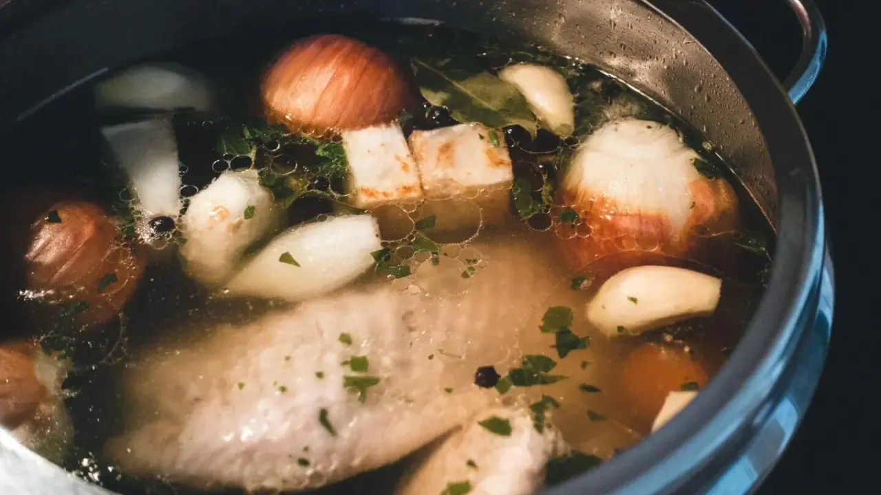 Szybkowar z bulionem: kawałki mięsa, cebula, czosnek, ziele angielskie i natka pietruszki tworzą aromatyczny rosół.