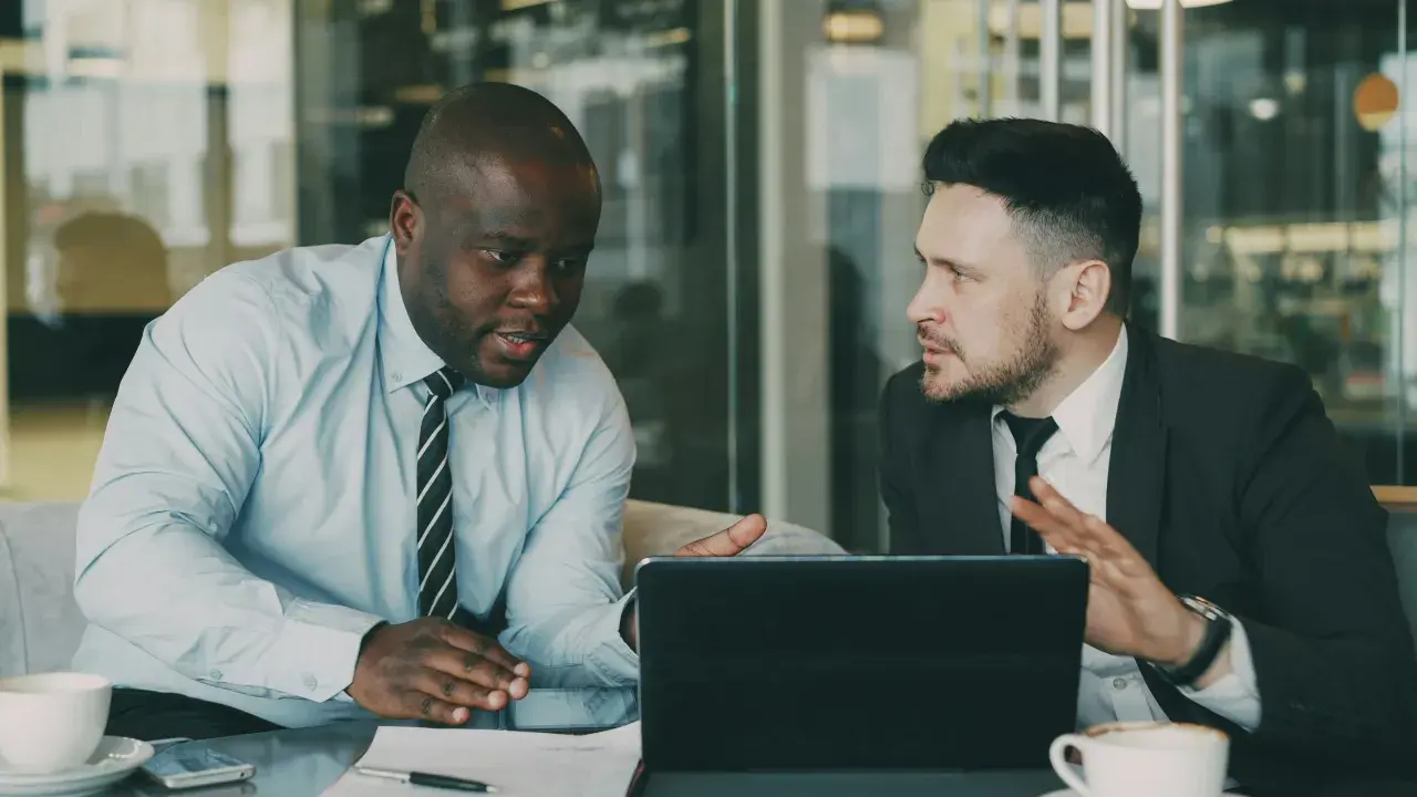 Deux hommes d'affaires discutent d'une nouvelle démarche, synonyme de succès. Ils sont concentrés sur une tablette.