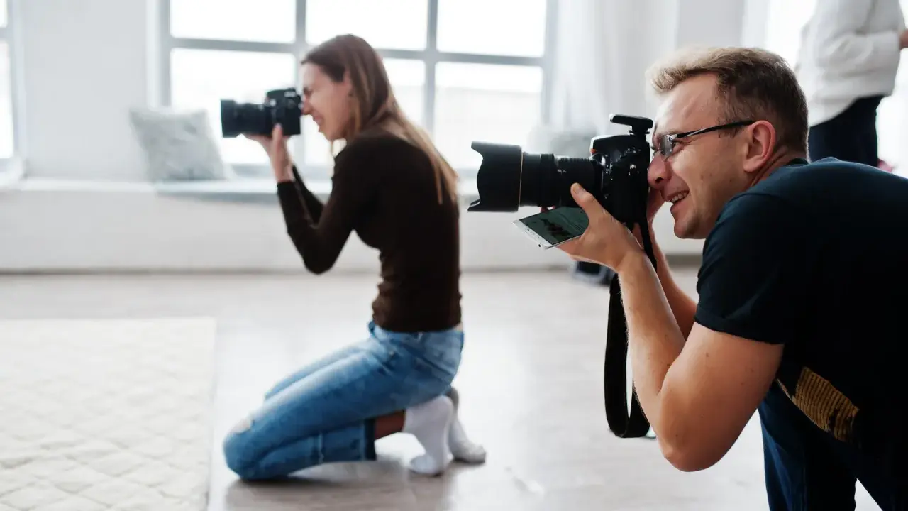 Mężczyzna i kobieta uczą się, jak zostać fotografem, ćwicząc z aparatami w studiu.