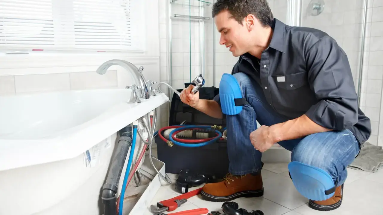Plombier vérifiant la pose de la baignoire, outils et tuyaux à proximité.
