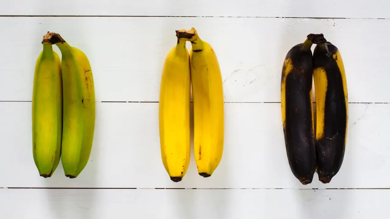 Drei Paare Bananen zeigen verschiedene Stadien der Reife: grün, gelb und überreif. So kann man sehen, wie Bananen lagern.