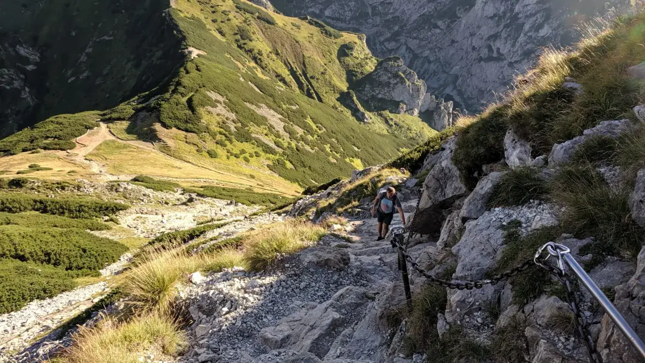 Turysta pokonuje kamienisty szlak z łańcuchami. Czy szlak na Giewont jest trudny? Ten odcinek wymaga ostrożności i dobrej kondycji.