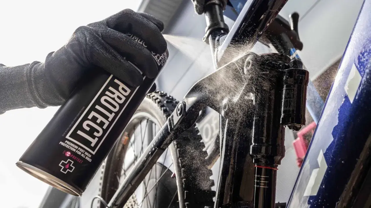 Rękawica z puszką "PROTECT" rozpyla środek na ramę roweru elektrycznego, pokazując, jak myć rower elektryczny.