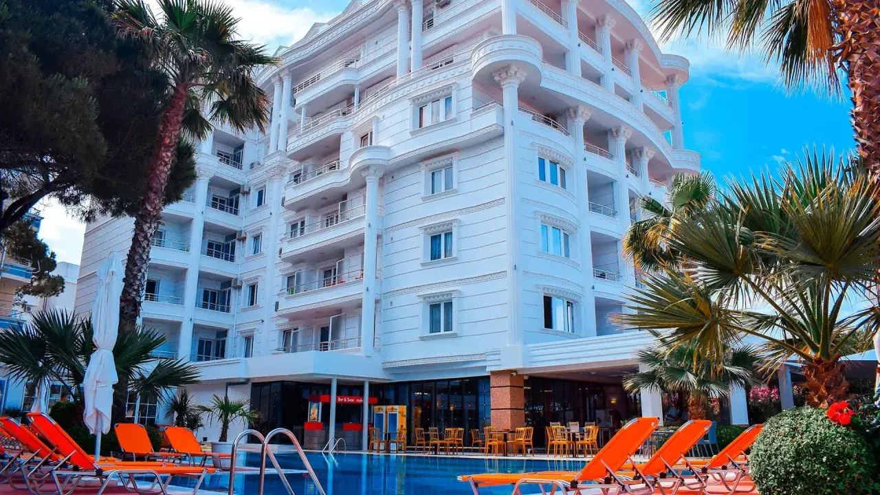 Biały hotel z balkonami i basenem, otoczony palmami. Idealne miejsce na fafa mel holiday.