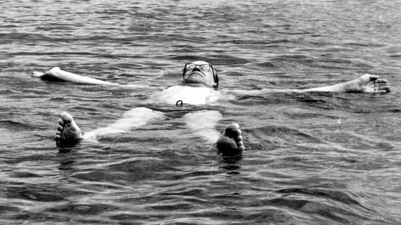 Tage Erlander, statsminister, flyter avslappnat på rygg i vattnet, med armarna utsträckta.