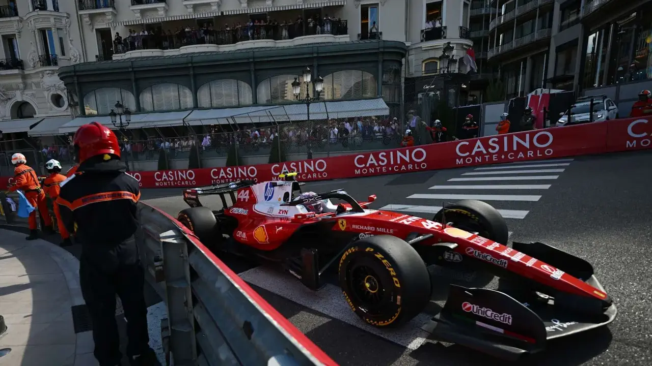 Lewis Hamilton im Ferrari-Boliden rast durch Monaco. Zuschauer säumen die Strecke, die Casino-Werbung blinkt.