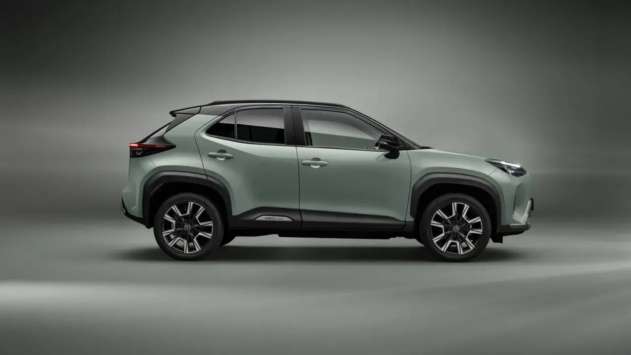 Nowy, zielony toyota crossover Yaris Cross z czarnym dachem i felgami stoi na szarym tle.