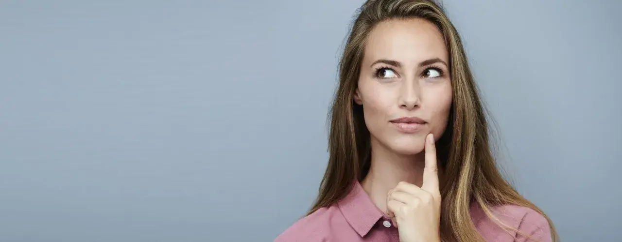Nachdenkliche Frau mit langen Haaren, die über die Vorteile von Keratin und Kreatin für die Haargesundheit sinniert.