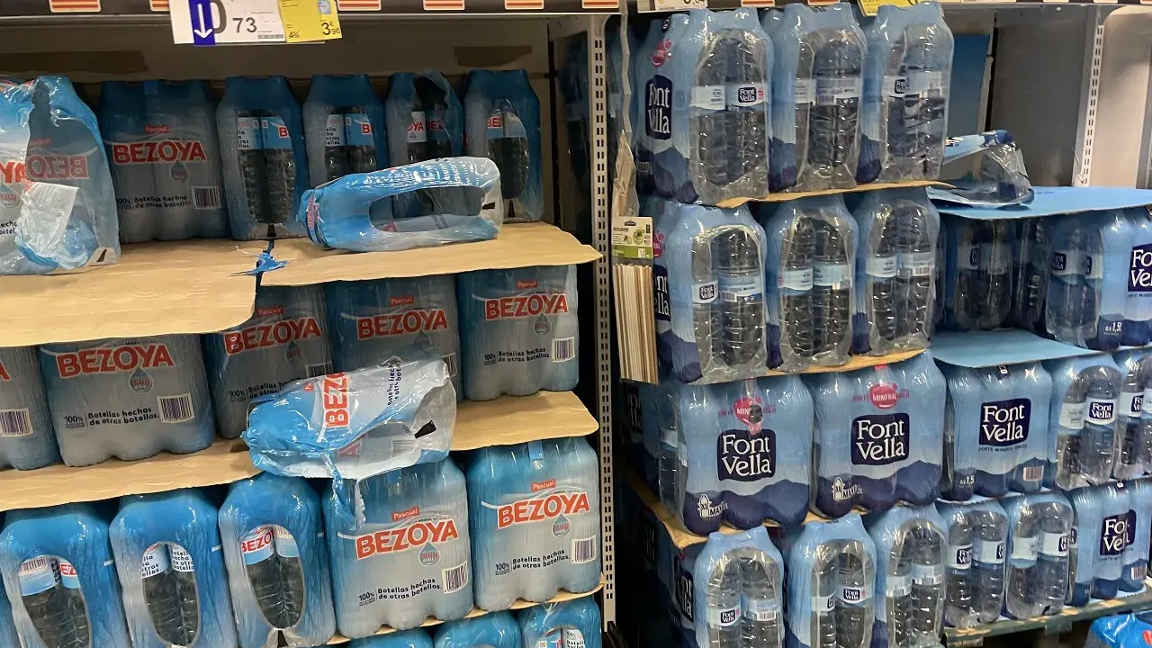 Scaffali pieni di bottiglie d'acqua in pacchi multipli. Il prezzo di 73 centesimi per una bottiglia d'acqua in crociera è un affare!