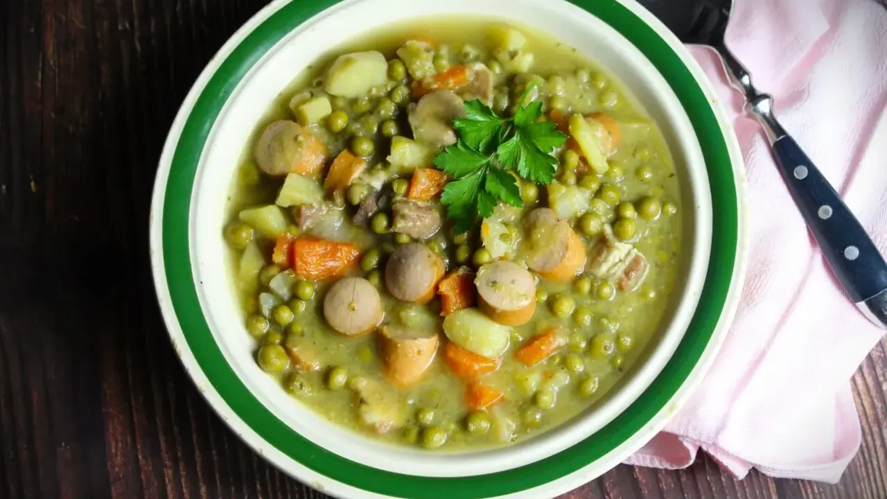 Herzhaftes Erbsensuppe Rezept mit Würstchen, Kartoffeln und Karotten, garniert mit Petersilie. Ein Klassiker für kalte Tage.