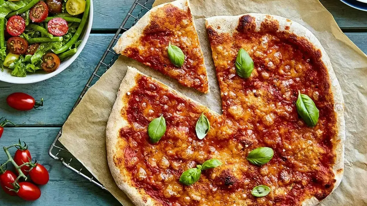 En härlig hemmagjord pizza med tomatsås och ost, toppad med färsk basilika. Bredvid en fräsch sallad med gröna bönor och körsbärstomater.