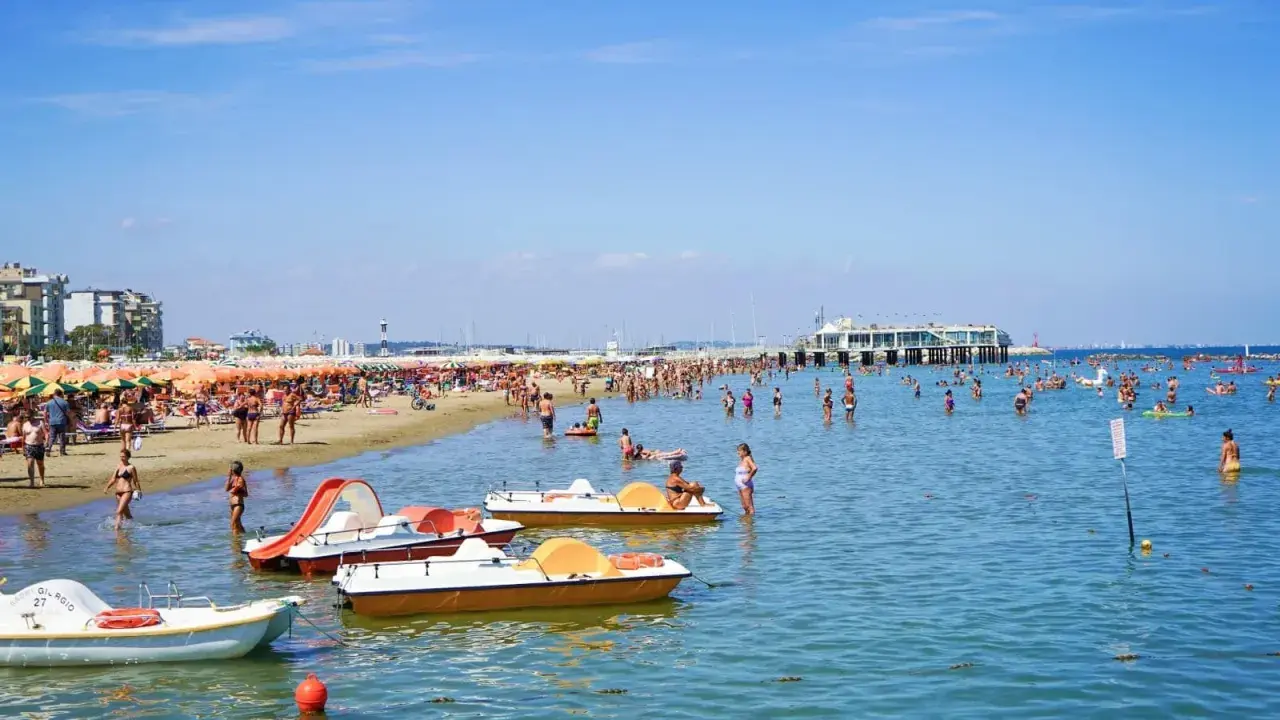 Spiaggia affollata a Gabicce, con ombrelloni colorati, gente in acqua e pedalò. Un'estate vivace al banana beach Gabicce.