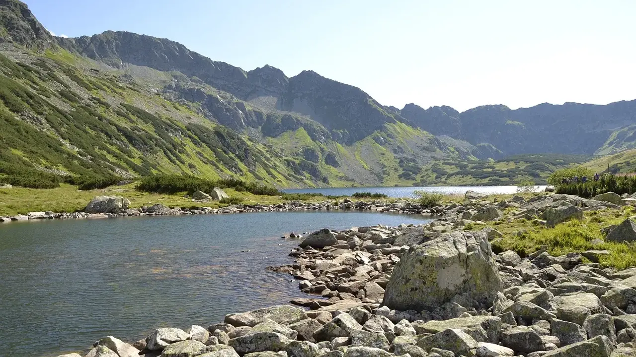 Kamieniste wybrzeże jeziora w Tatrach, idealne na wędrówkę szlakami turystycznymi Zakopane.