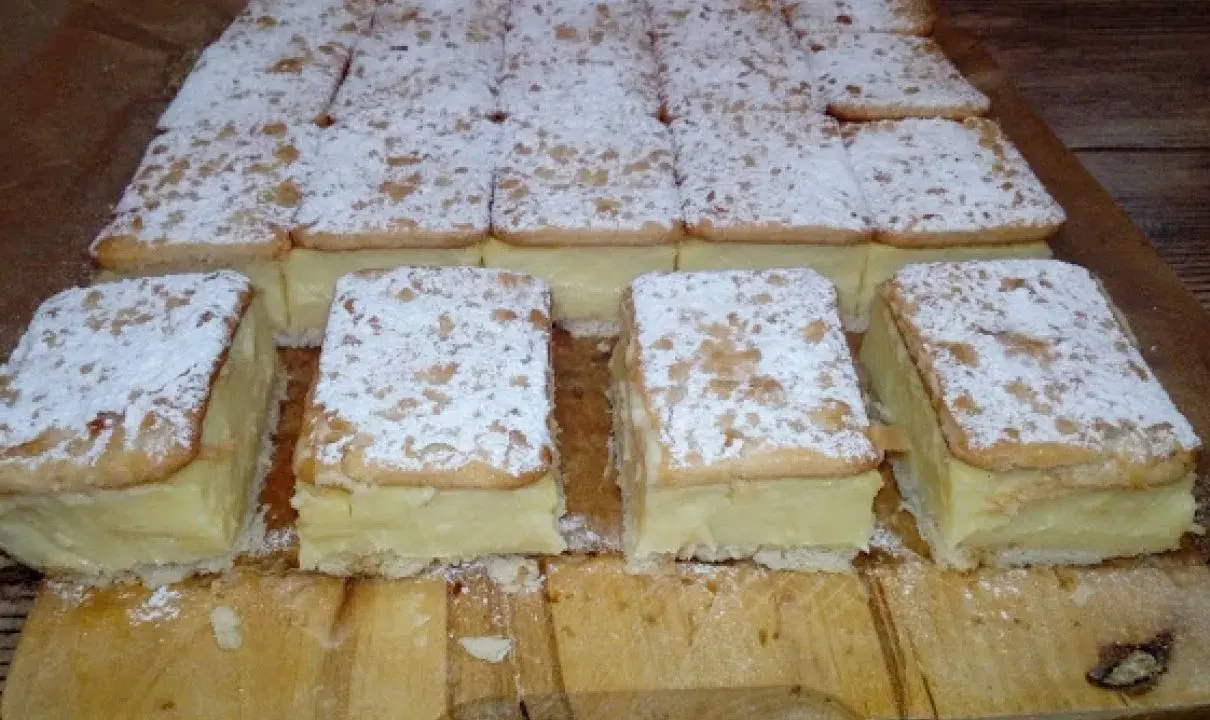Pyszne napoleonki na krakersach, posypane cukrem pudrem, czekają na spróbowanie.