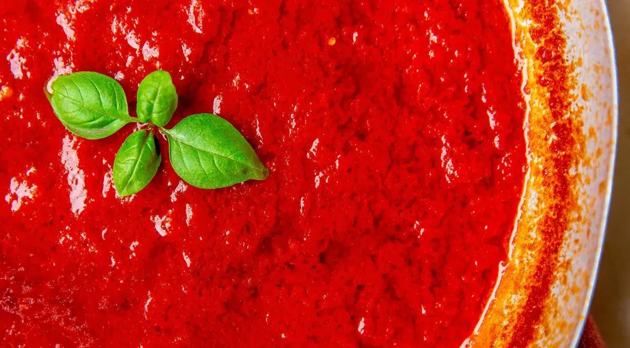 San Marzano Tomatensoße, perfekt für jedes Rezept. Ein Hauch frisches Basilikum rundet das Bild ab.