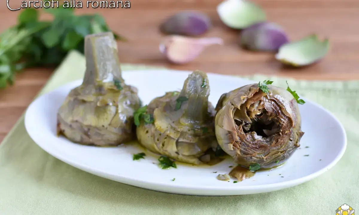 Tre carciofi alla romana cotti, serviti su un piatto bianco con prezzemolo tritato. Sullo sfondo, spicchi d'aglio e foglie di carciofo.