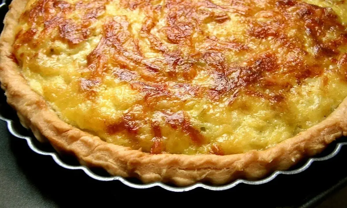 Une tarte aux poireaux dorée et appétissante, prête à être dégustée. Sa croûte croustillante et sa garniture onctueuse invitent au partage.