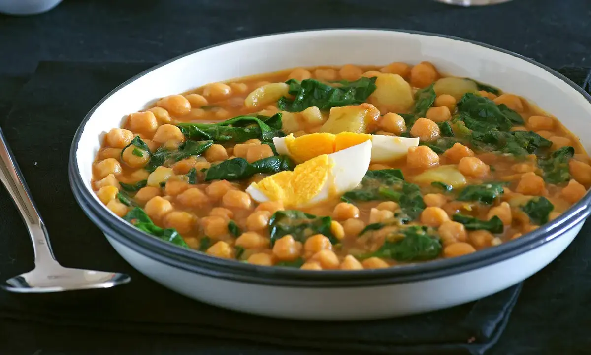Un plato humeante de garbanzos con espinacas y huevo duro, una de las muchas deliciosas recetas con garbanzos.