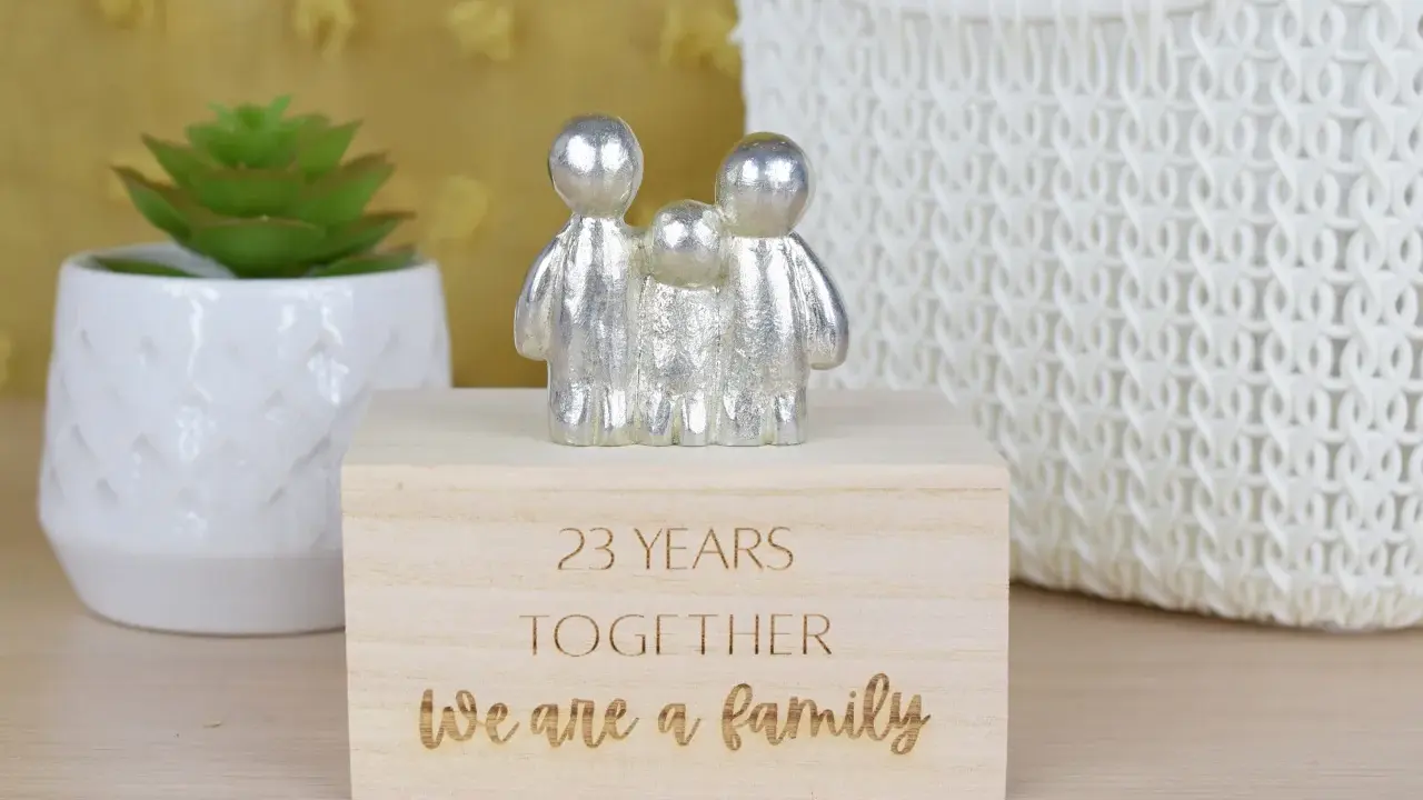 Srebrna figurka rodziny na drewnianym pudełku z napisem "23 YEARS TOGETHER We are a family". Idealny prezent na 23 rocznicę ślubu.