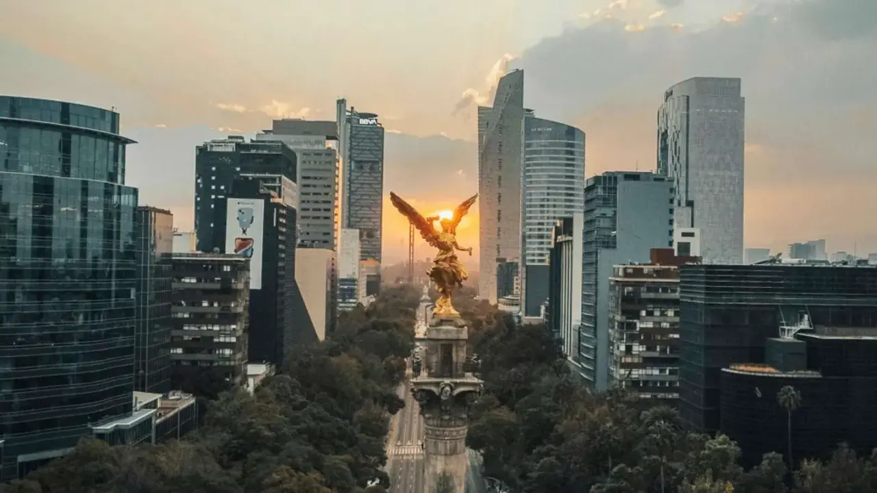 Goldene Viktoria-Statue im Sonnenuntergang, umgeben von modernen Wolkenkratzern in Mexico City.