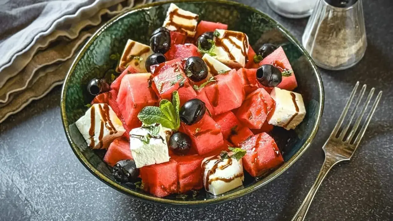 Erfrischender Melonen Feta Salat mit schwarzen Oliven und Minze, beträufelt mit Balsamico-Dressing. Perfekt für heiße Tage!