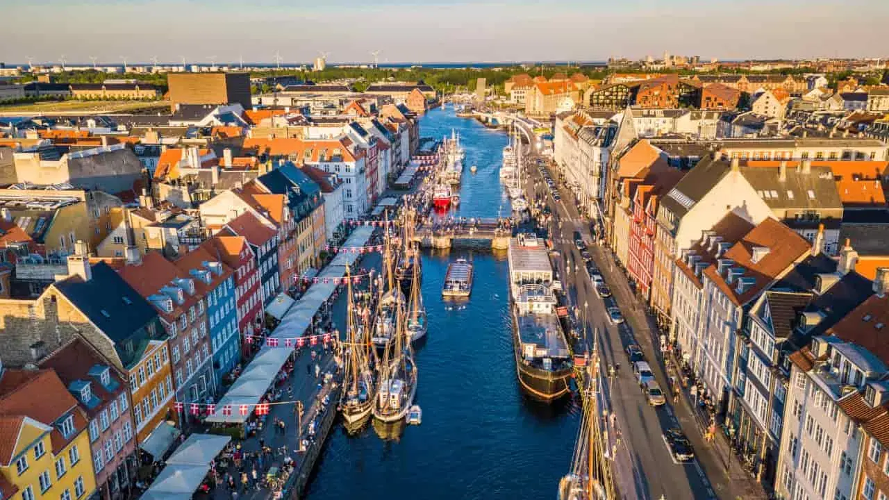Navigazione nel porto di Copenaghen, con case colorate, barche a vela e un vivace lungomare.
