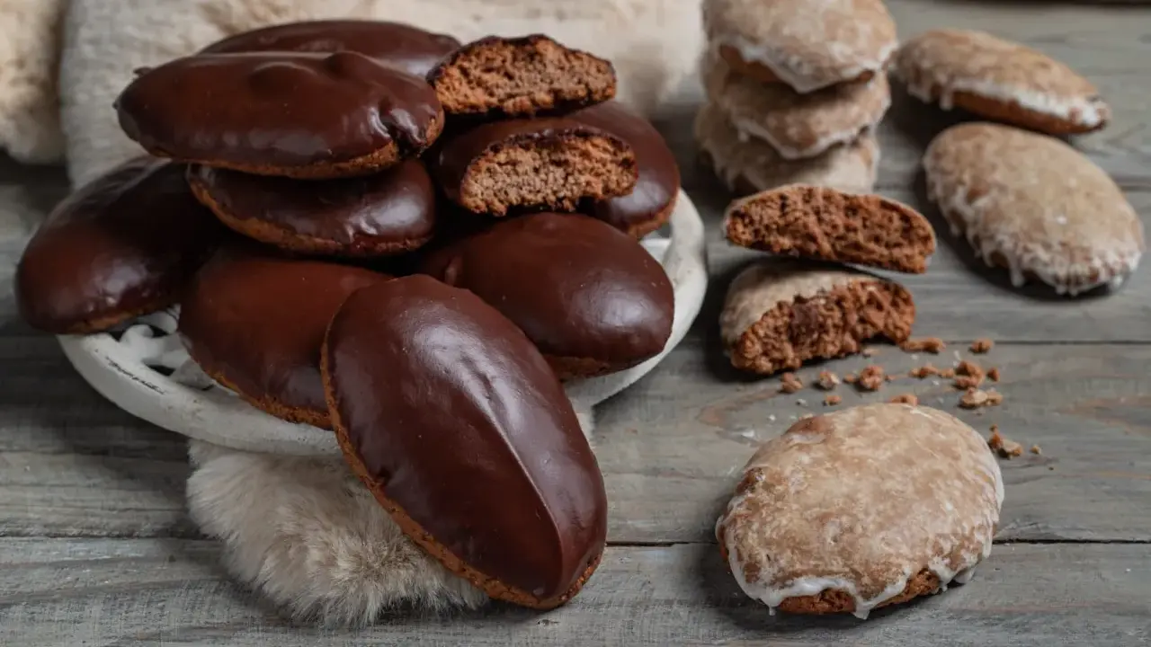 Biscotti tipici calabresi, alcuni ricoperti di cioccolato fondente, altri glassati, su un tavolo di legno.