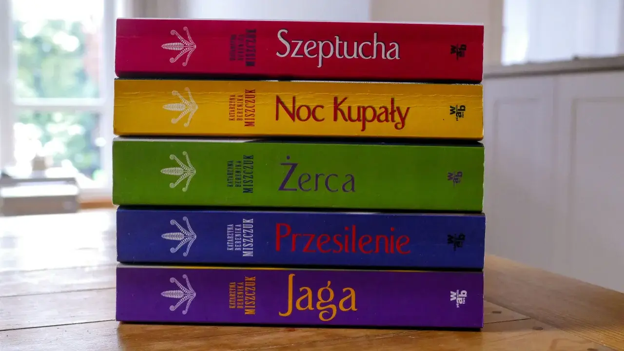 Pięć kolorowych książek Katarzyny Bereniki Miszczuk ułożonych jedna na drugiej. Na okładkach widnieje symbol kwiatu paproci.